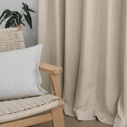 Helen oatmeal curtains draping softly beside a wooden lounge chair with neutral cushions