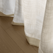 Close-up of warm ivory linen-look curtain hem showing its textured weave and natural drape