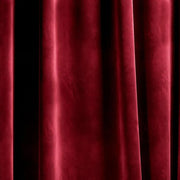 Close-up of burgundy velvet curtain fabric showing its soft sheen and flowing folds