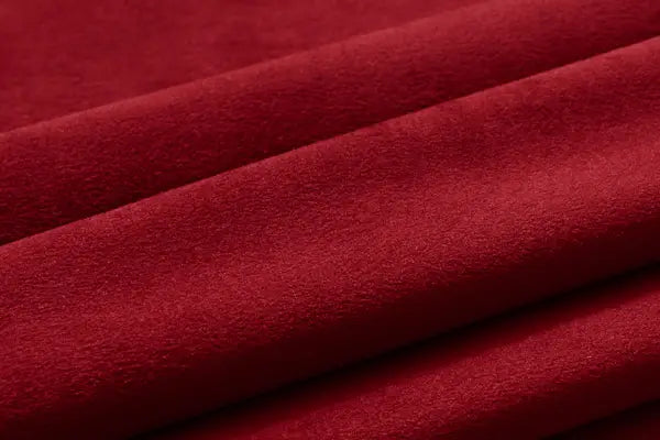 Close-up of red velvet curtain fabric with a soft, fine pile and smooth folds