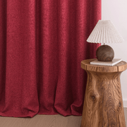 Helen burgundy room darkening curtains with natural folds pooling on the floor beside a wooden stool