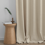 Oatmeal linen-look curtains with soft flowing folds beside a wooden side table