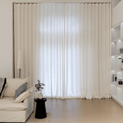 Warm ivory linen-look curtains softly filtering daylight beside a white sofa in a bright living room